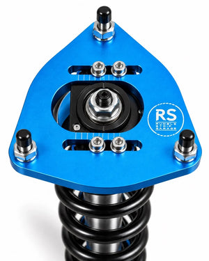 A close-up of a blue anodized aluminum suspension component with a black coil spring, featuring a circular RS Suspension Sturdi Case logo on the side.