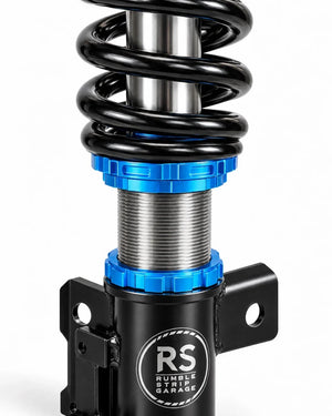 Close-up of a black and silver coilover shock absorber with bright blue anodized accents and a visible 'RS Rumble Strip Garage' logo on the body, set against a clean white background.